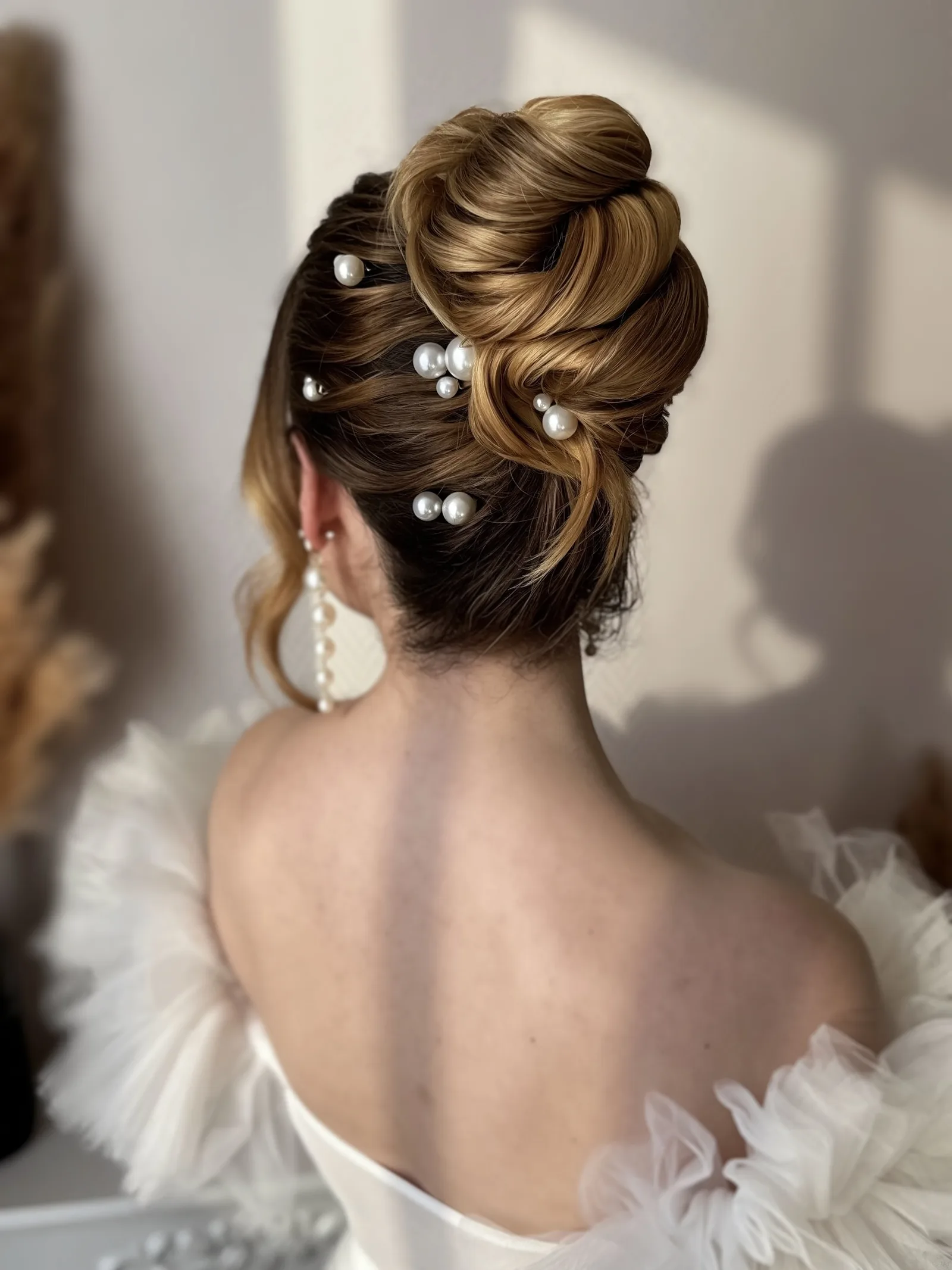 Chignon haut torsadé orné de perles, réalisé par Marine en formation